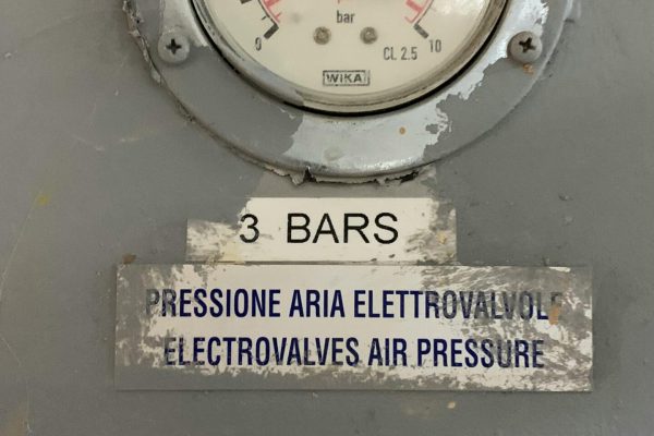 Close-up of a pressure gauge showing 3 bars in an industrial setting.