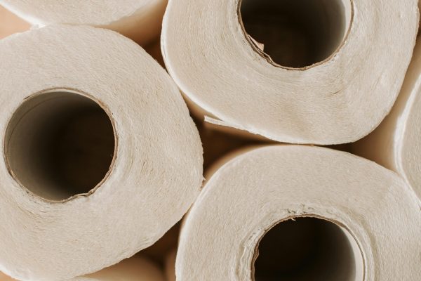 Top view of multiple toilet paper rolls arranged on a wooden surface, offering ample copy space.